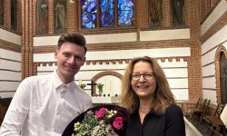 Eine Frau und ein Mann tauschen lächelnd in einer Kirche einen Blumenstrauß aus.