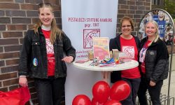 Drei Frauen lachen in die Kamera. Sie stehen an einem Bistro-Tisch an einer Backstein-Wand, davor rote Ballons und dahinter ein weißes Banner mit dem Logo der Pestalozzi-Stiftung Hamburg