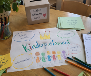Zeichnung "Kinderparlament" auf Tisch, mit Malstiften und ähnlichem